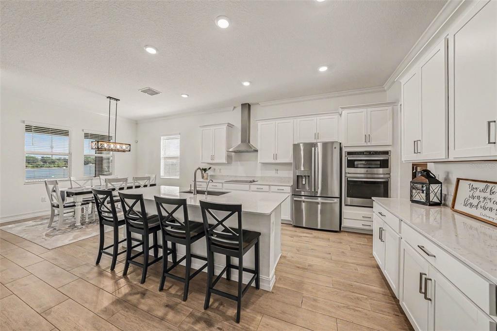 A modern kitchen features white cabinets, a large island with bar seating, and stainless appliances — 12840 BERGSTROM BAY DRIVE, RIVERVIEW, FL