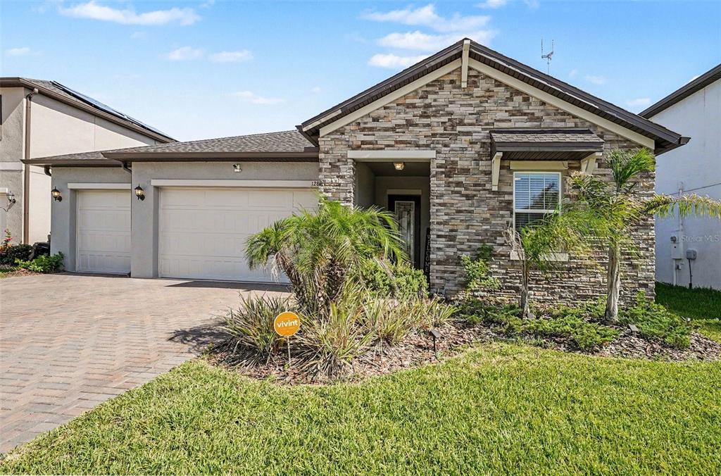 A single-story house with a stone facade, a two-car garage, and a paved driveway — 12840 BERGSTROM BAY DRIVE, RIVERVIEW, FL