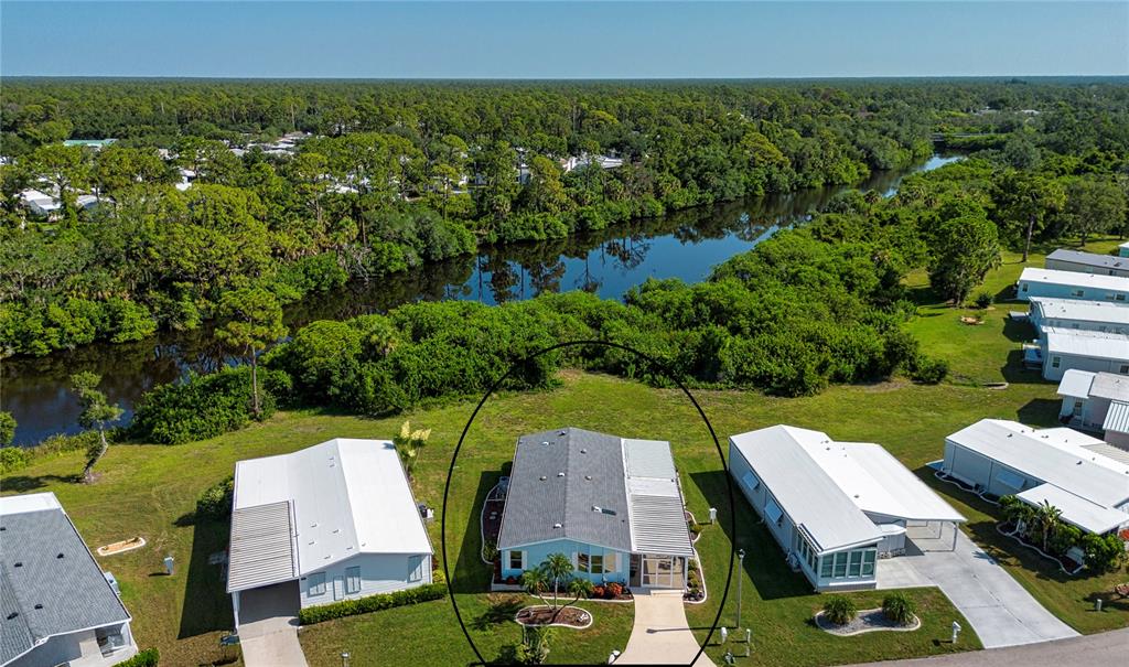 An aerial view shows a light blue mobile home circled in a residential waterfront community — 608 PORTSIDE DRIVE, NORTH PORT, FL
