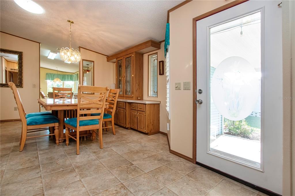 A dining area features a wooden table, chairs with teal cushions, and a built-in hutch — 608 PORTSIDE DRIVE, NORTH PORT, FL