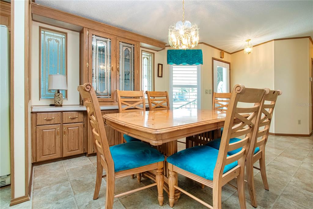 A dining room features a wooden table and chairs with blue cushions and built-in cabinetry — 608 PORTSIDE DRIVE, NORTH PORT, FL