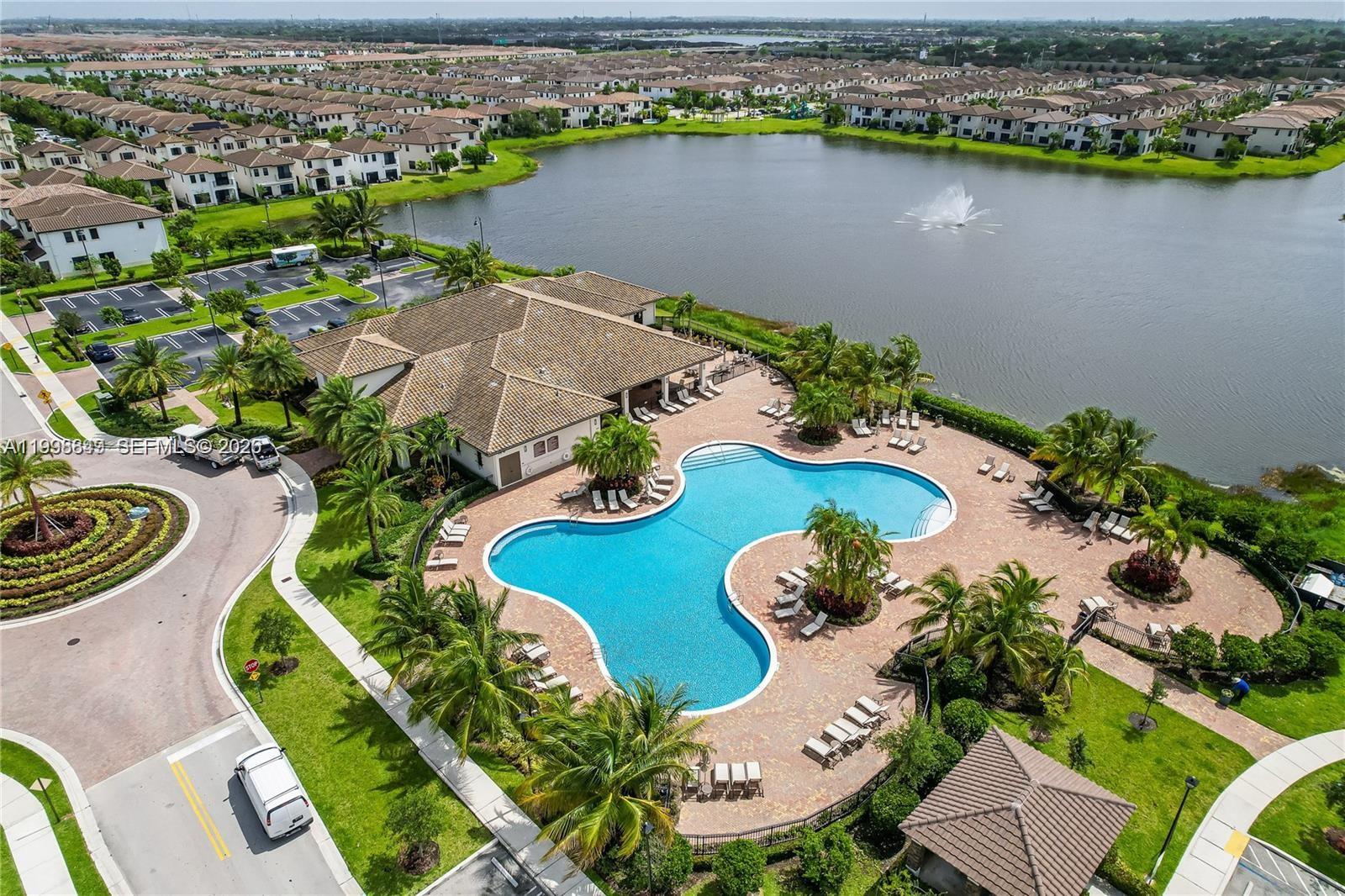 An aerial view shows a community clubhouse with a pool, fountain, and surrounding suburban homes — 3564 W 97th St, Hialeah FL 33018, HIALEAH, FL