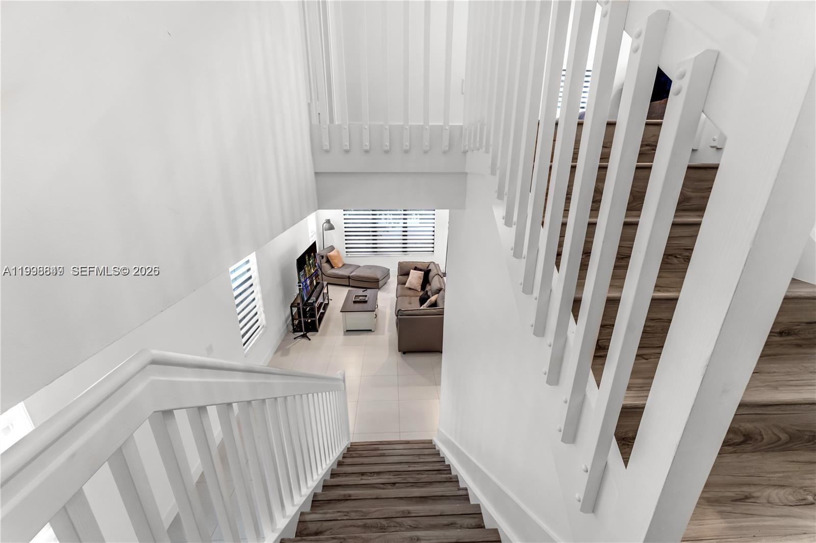 A high-angle view shows a staircase with wood treads leading down to a living room — 3564 W 97th St, Hialeah FL 33018, HIALEAH, FL