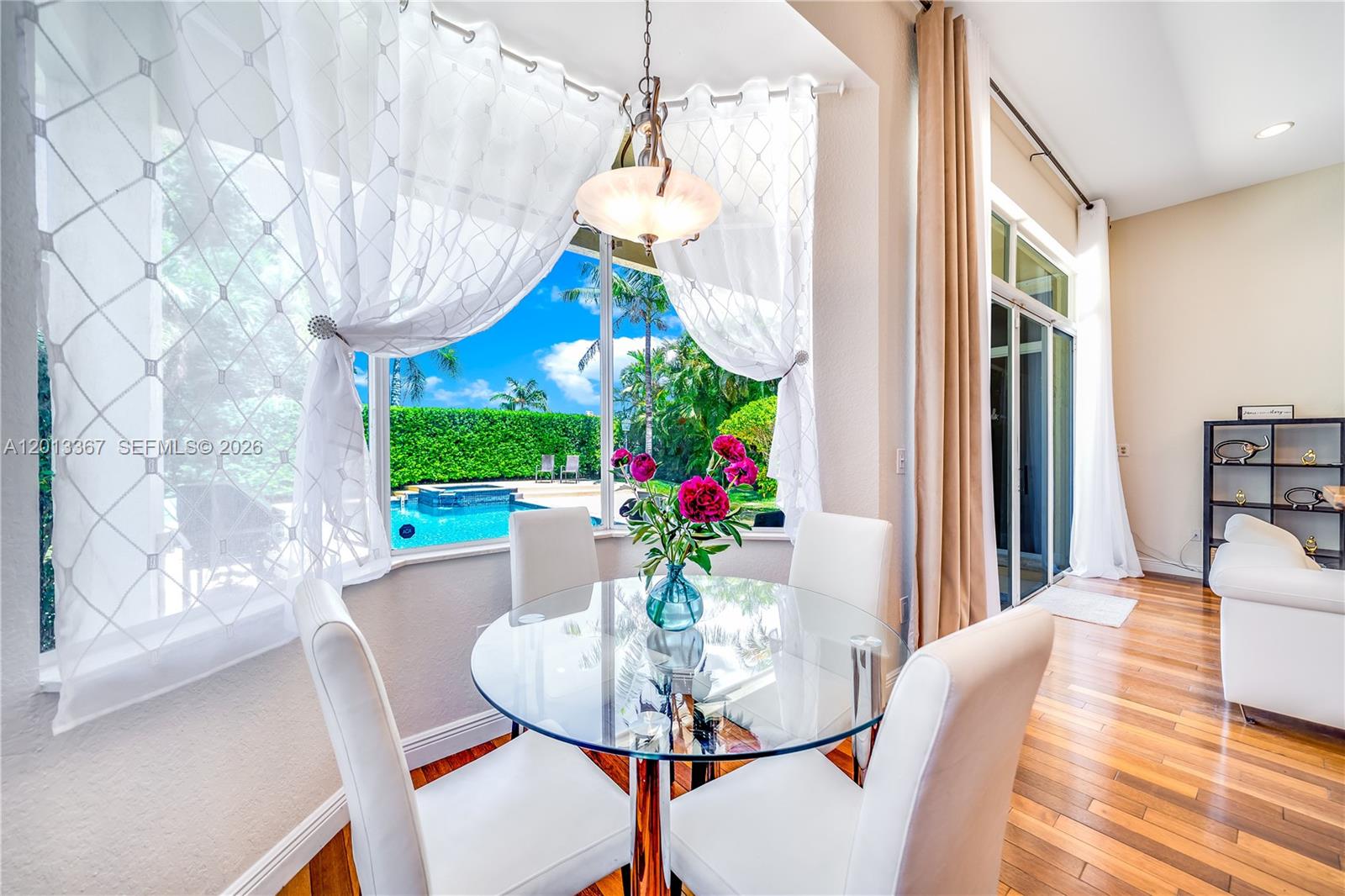 A breakfast nook features a glass table, white chairs, and a view of a pool — 1241 S 13th Ave, Hollywood FL 33019, HOLLYWOOD, FL