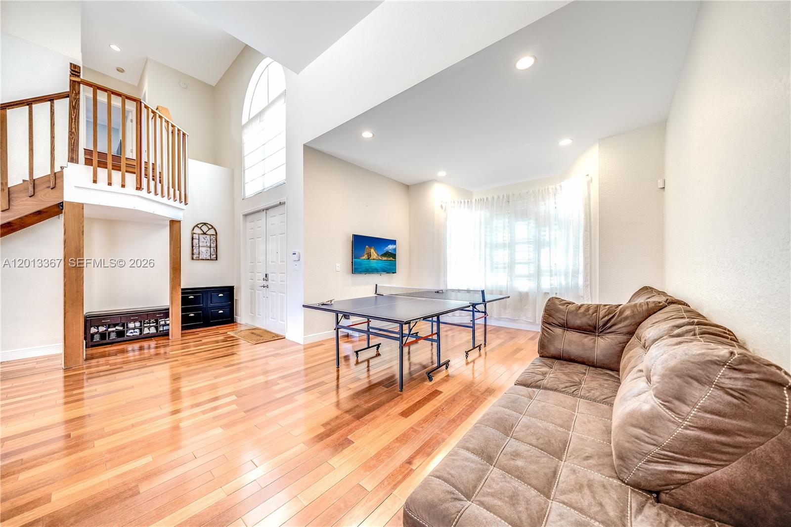 A spacious living area features hardwood floors, a ping pong table, and a wooden staircase — 1241 S 13th Ave, Hollywood FL 33019, HOLLYWOOD, FL