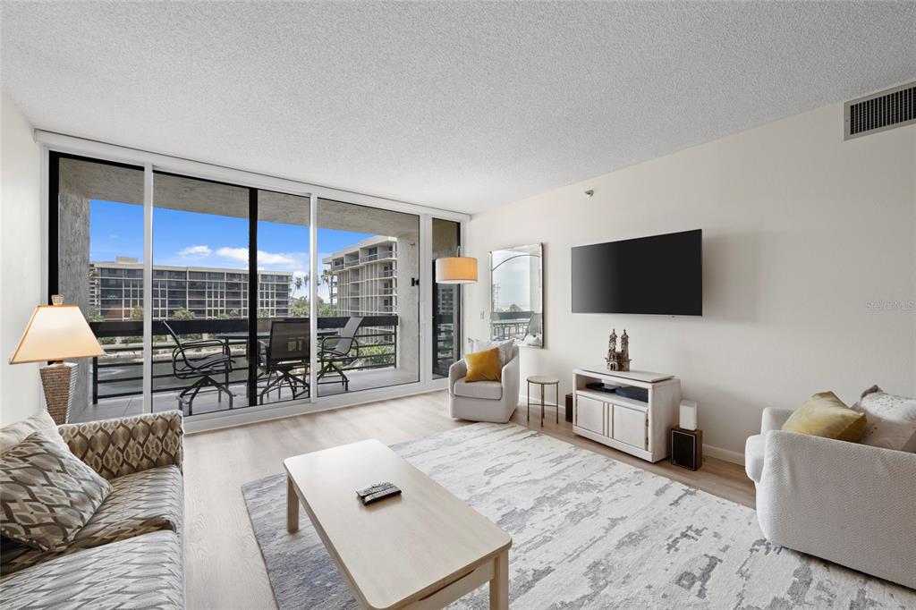 A multi-story beige apartment building features stacked balconies and a ground-level covered entrance — 1095 GULF OF MEXICO DRIVE UNIT 303, LONGBOAT KEY, FL