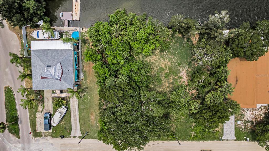 An aerial view shows a vacant, tree-covered lot situated between two houses along a waterway — Lot 15 RICE ROAD, HUDSON, FL