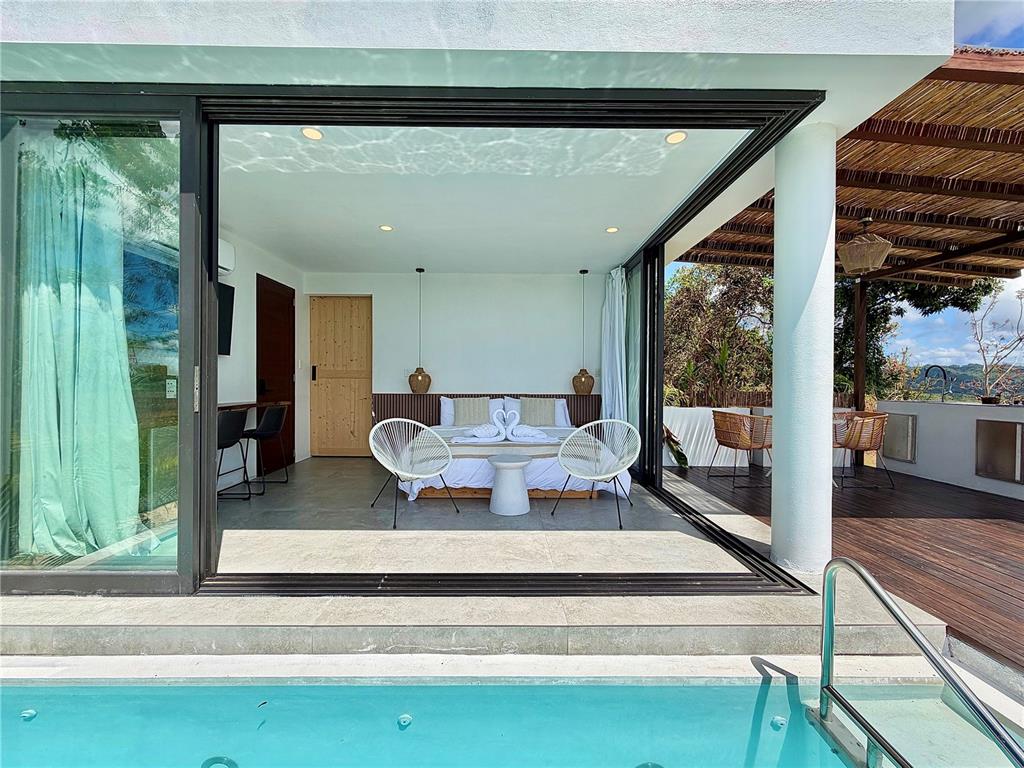 A bedroom with a pool view features sliding glass doors, white walls, and tiled floors — Lot 1 KM. 8.0 INT. CRUZ WARD, MOCA, PR