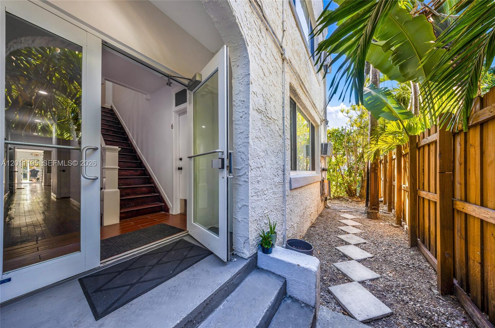 An open glass door reveals a staircase leading to an interior hallway with wooden floors — 1610 Salzedo St, Coral Gables FL 33134, CORAL GABLES, FL