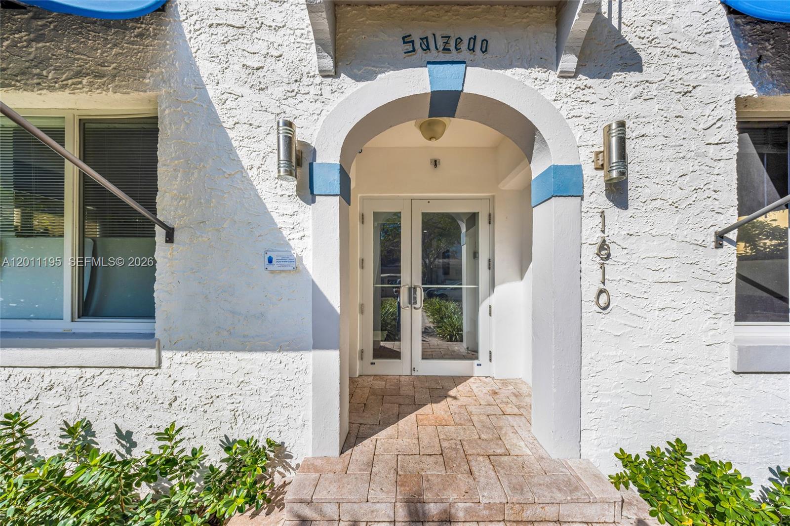 The exterior entrance features a white stucco facade, an arched doorway, and double glass doors — 1610 Salzedo St, Coral Gables FL 33134, CORAL GABLES, FL