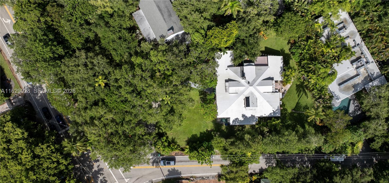 An aerial view shows a house with a complex roofline surrounded by dense trees — 1701 S Bayshore Drive, Miami FL 33133, MIAMI, FL