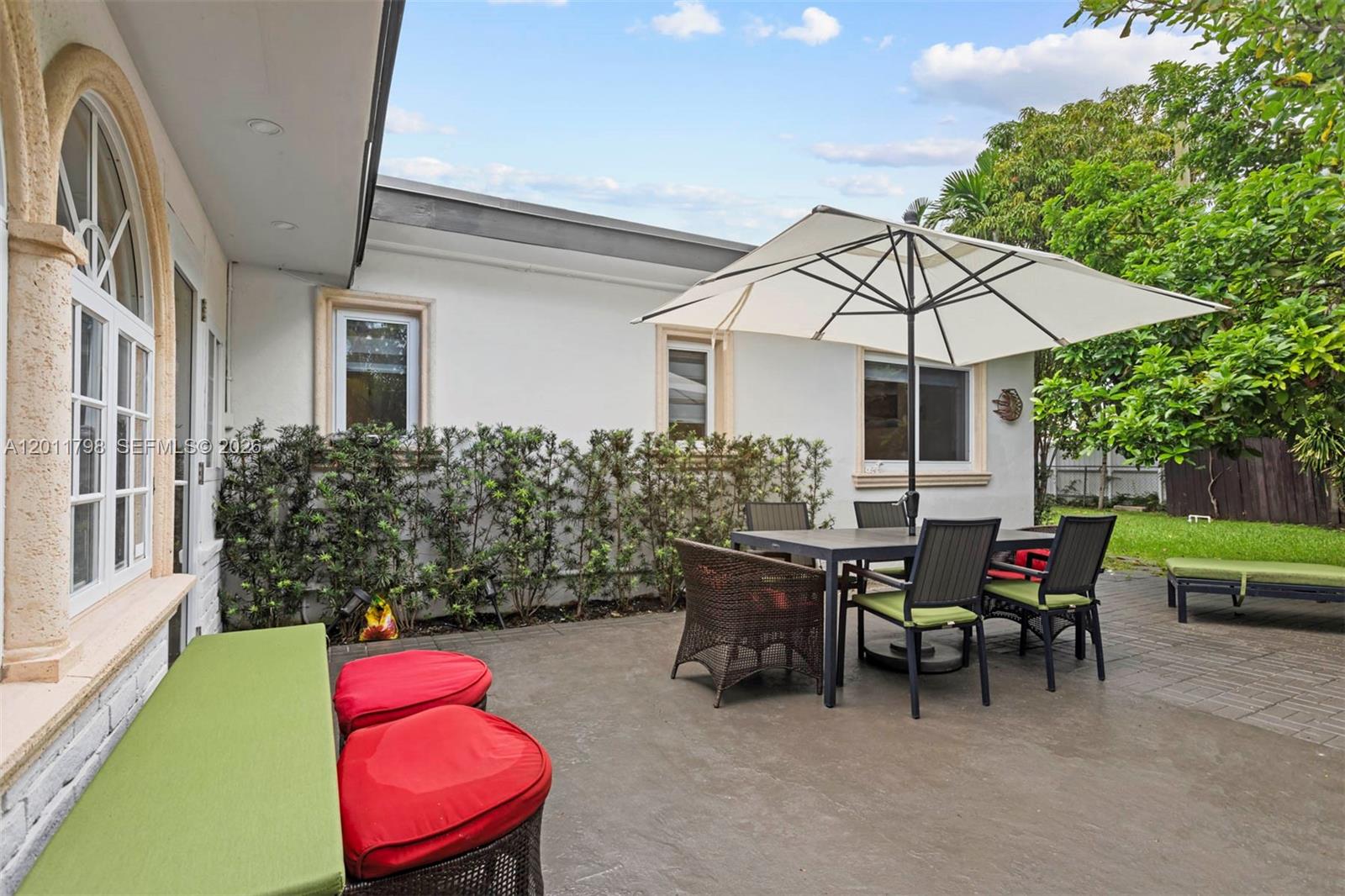 A patio area features a dining set with an umbrella, a bench, and landscaping — 6921 Trouville Esplanade, Miami Beach FL 33141, MIAMI BEACH, FL