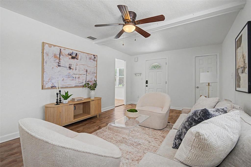 A bright living room features white walls, wood flooring, a ceiling fan, and modern furniture — 3913 N LYNN AVENUE, TAMPA, FL