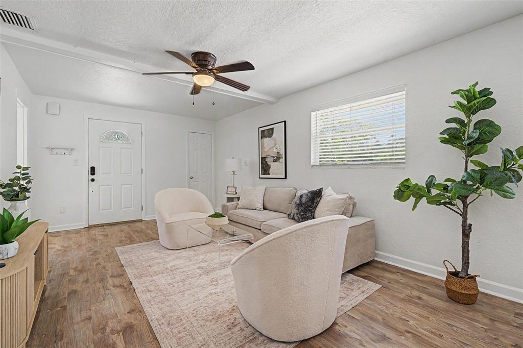 A living room features light wood flooring, a ceiling fan, a sofa, and two armchairs — 3913 N LYNN AVENUE, TAMPA, FL