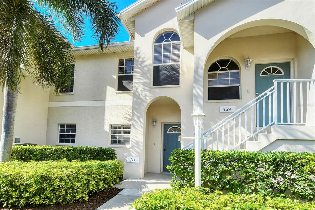 The exterior of a two-story stucco building features two blue front doors and arched windows — 8370 WINGATE DRIVE UNIT 724, SARASOTA, FL