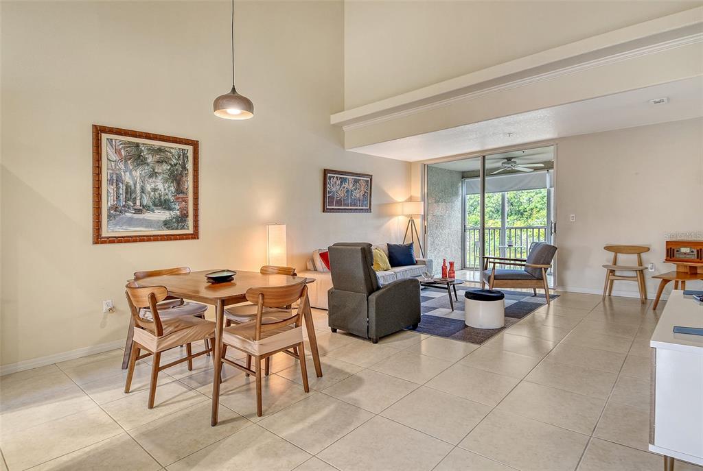 A living and dining area with tile floors, high ceilings, and a sliding glass door — 8370 WINGATE DRIVE UNIT 724, SARASOTA, FL