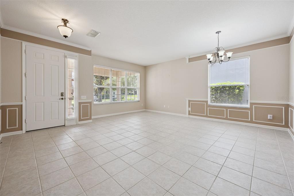 An empty room with light-colored tile flooring, wainscoting, a chandelier, and a front door — 8662 ABBOTSBURY DRIVE, WINDERMERE, FL