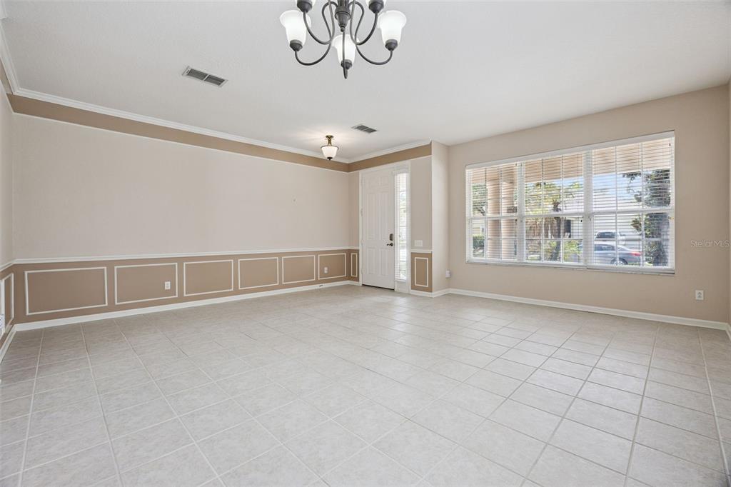 A bright, tiled dining room features wainscoting, a chandelier, and a large window — 8662 ABBOTSBURY DRIVE, WINDERMERE, FL