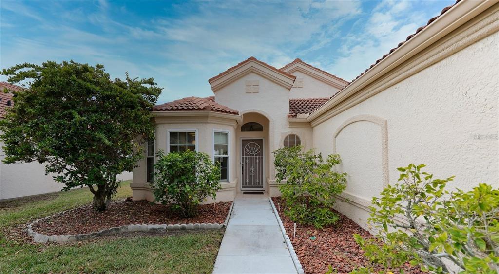 A single-story house with a stucco exterior, tile roof, and a concrete walkway to the entrance — 718 LIGHTHOUSE DRIVE, TARPON SPRINGS, FL