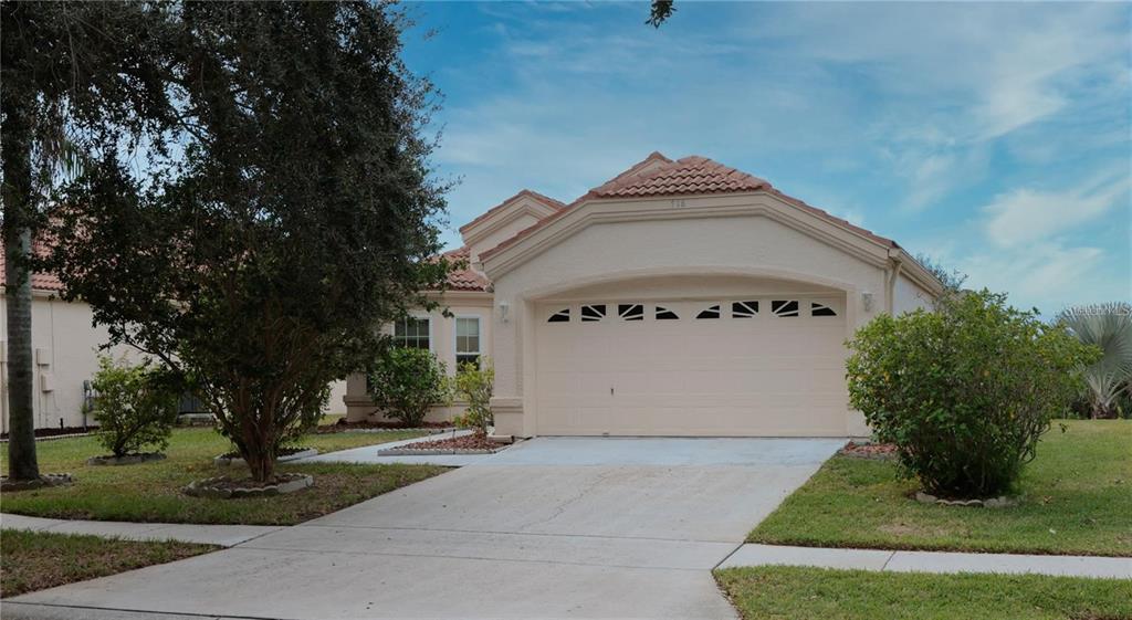 A beige single-story house with a two-car garage and a tiled roof — 718 LIGHTHOUSE DRIVE, TARPON SPRINGS, FL