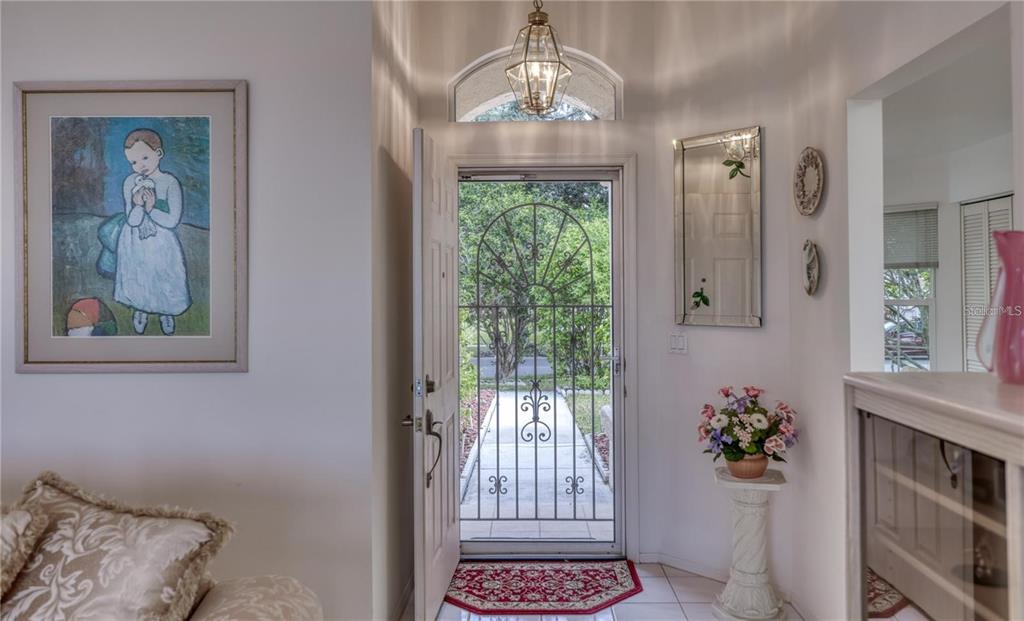 An entryway features a white door with a decorative metal screen, tile floors, and artwork — 718 LIGHTHOUSE DRIVE, TARPON SPRINGS, FL