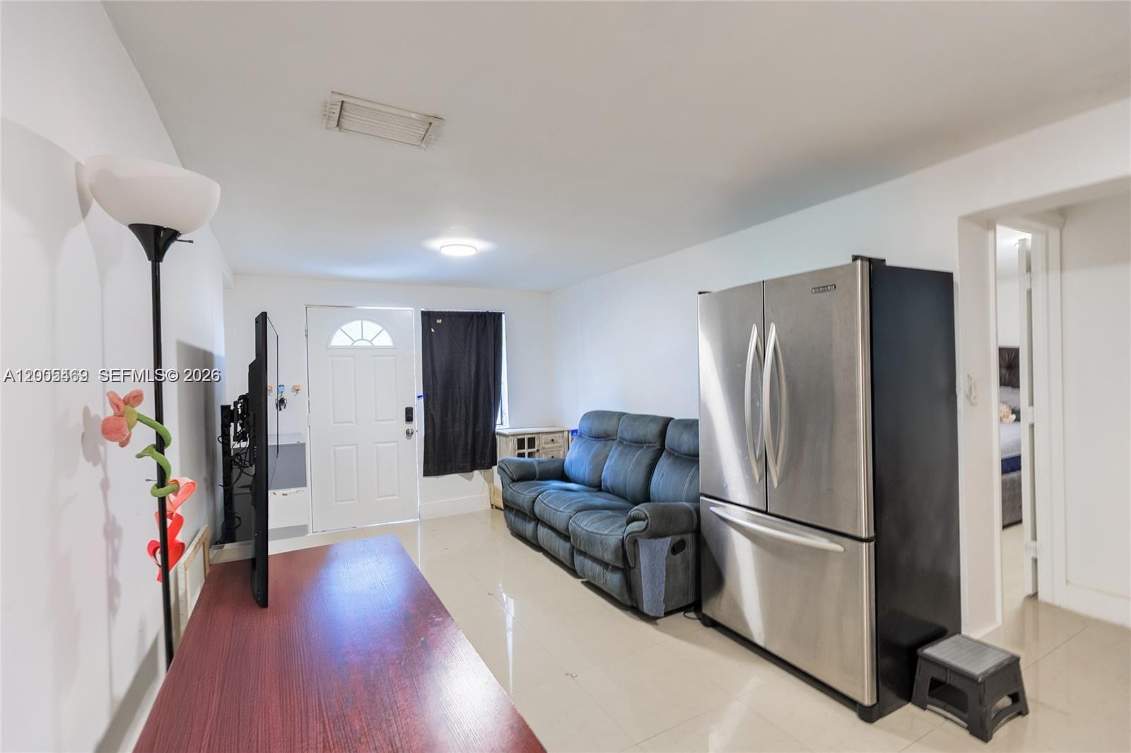 A living area features a blue sofa, a stainless steel refrigerator, and a television — 14601 NW 10th Ave # 2, Miami FL 33168, MIAMI, FL