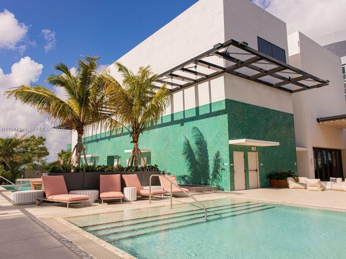 A swimming pool with lounge chairs sits in front of a building with green tiles — 11 NE 6 ST # 814, Miami FL 33132, MIAMI, FL