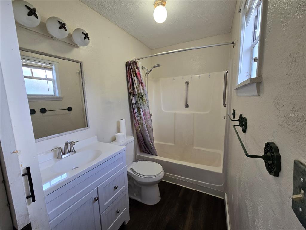 A bathroom features a white vanity, a toilet, and a shower-tub combination with a curtain — 665 SE HERON STREET, KEYSTONE HEIGHTS, FL