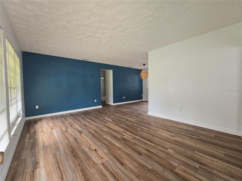 An empty room features blue accent walls, white trim, and wood-look laminate flooring — 665 SE HERON STREET, KEYSTONE HEIGHTS, FL