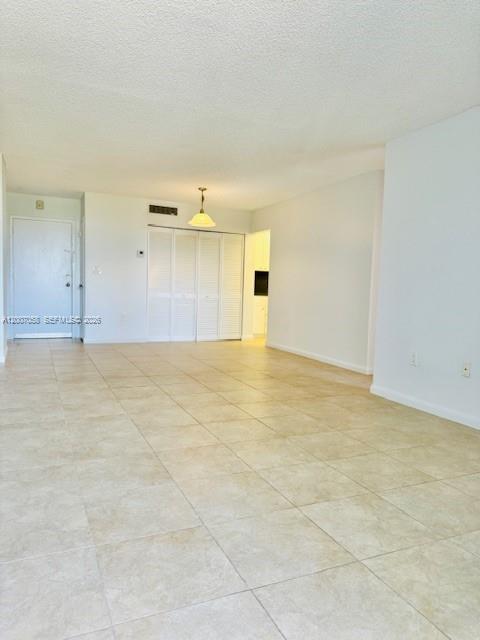 An empty room features light-colored tile flooring, white walls, and a sliding closet door — NORTH MIAMI, FL