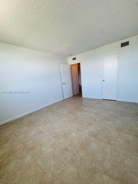 An empty room with beige tile flooring, white walls, and two closed white doors — NORTH MIAMI, FL