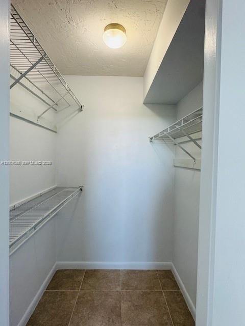 A walk-in closet features white walls, wire shelving, and tan tile flooring — NORTH MIAMI, FL
