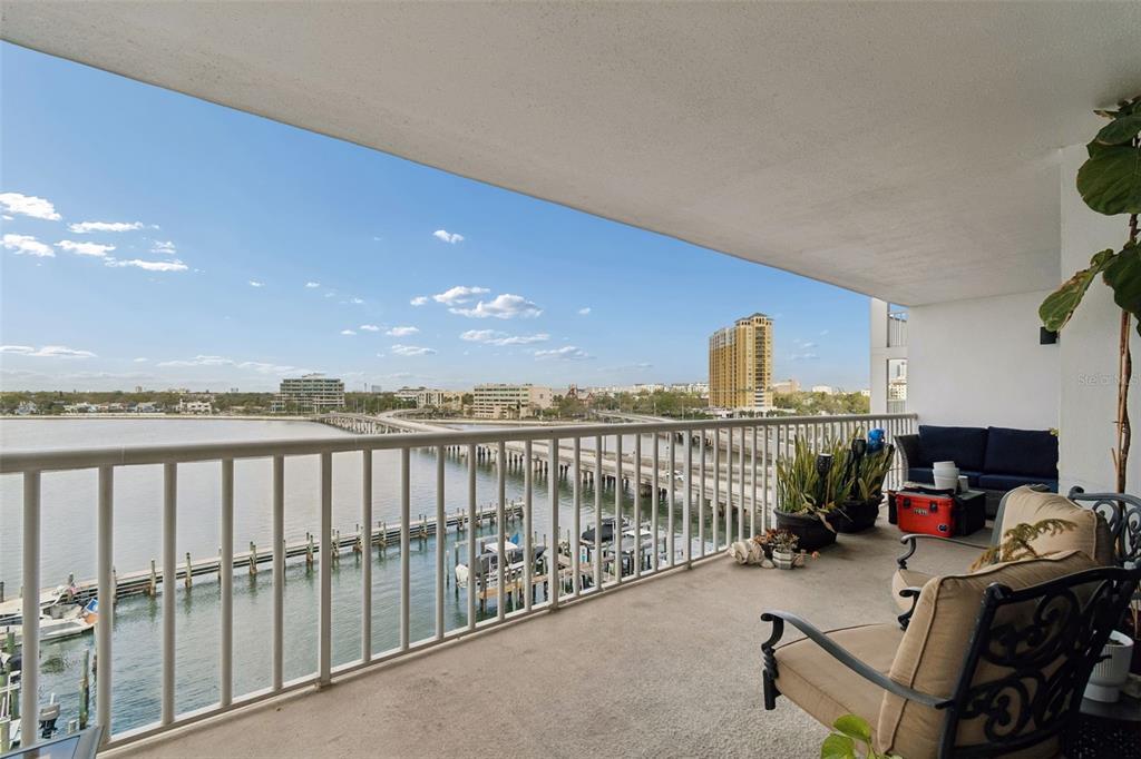 A balcony with outdoor furniture overlooks a bay, a bridge, and a marina — 2 ADALIA AVENUE UNIT 704, TAMPA, FL