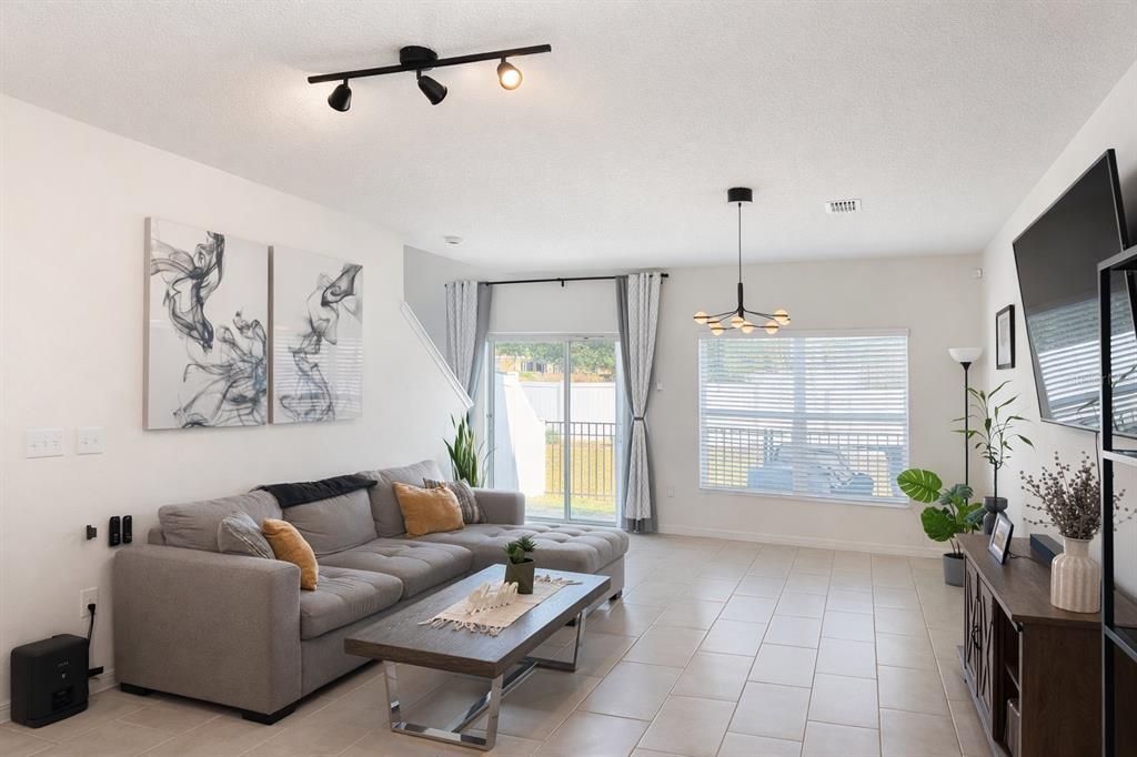 A living room features a gray sectional sofa, a coffee table, and a television — 1536 MIRABELLA CIRCLE UNIT 1536, DAVENPORT, FL
