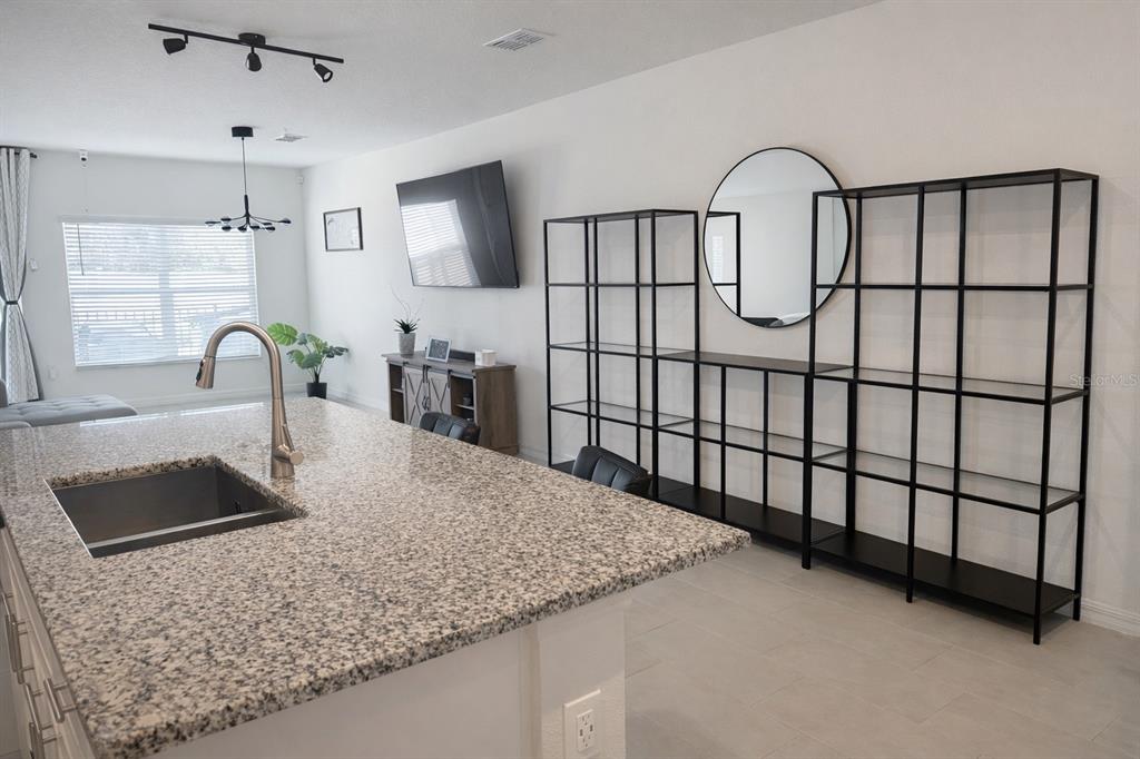 A kitchen island with a granite countertop sits in front of open black metal shelving — 1536 MIRABELLA CIRCLE UNIT 1536, DAVENPORT, FL