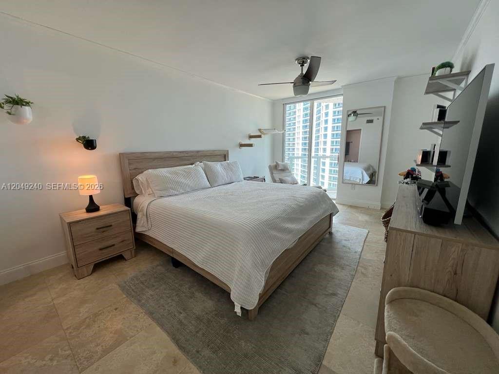 A bedroom features a wooden bed frame, a ceiling fan, and a large window — 5900 Collins Ave # 1406, Miami Beach FL 33140, MIAMI BEACH, FL