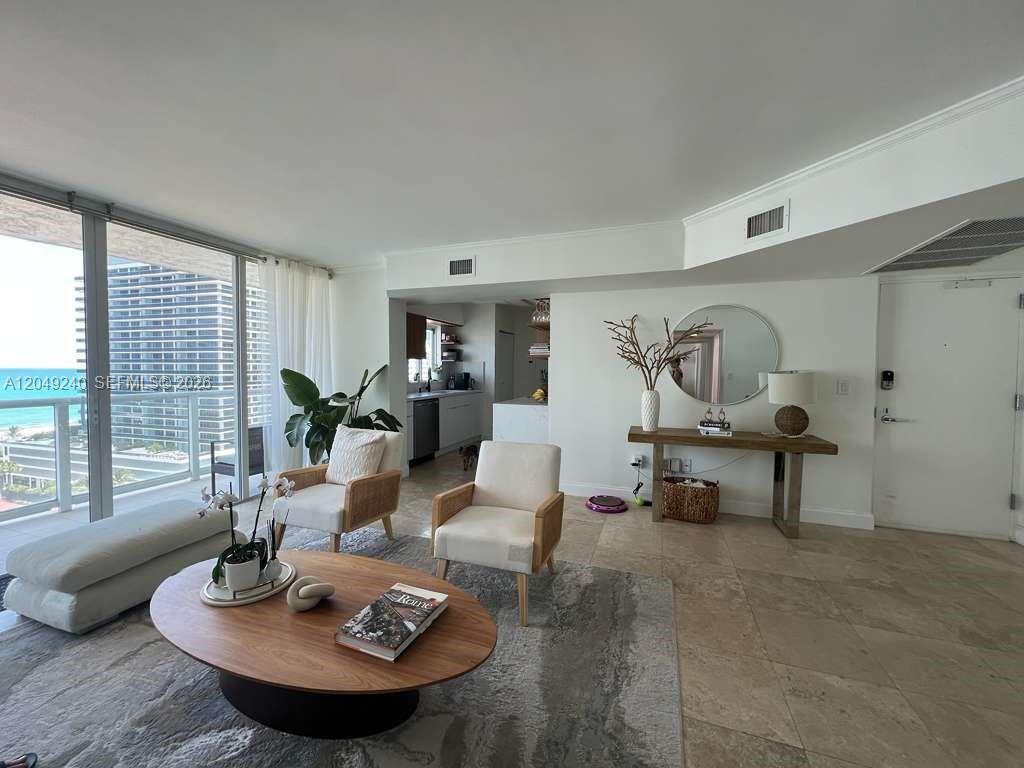 A living room with tile floors, a wooden coffee table, and a view of the ocean — 5900 Collins Ave # 1406, Miami Beach FL 33140, MIAMI BEACH, FL