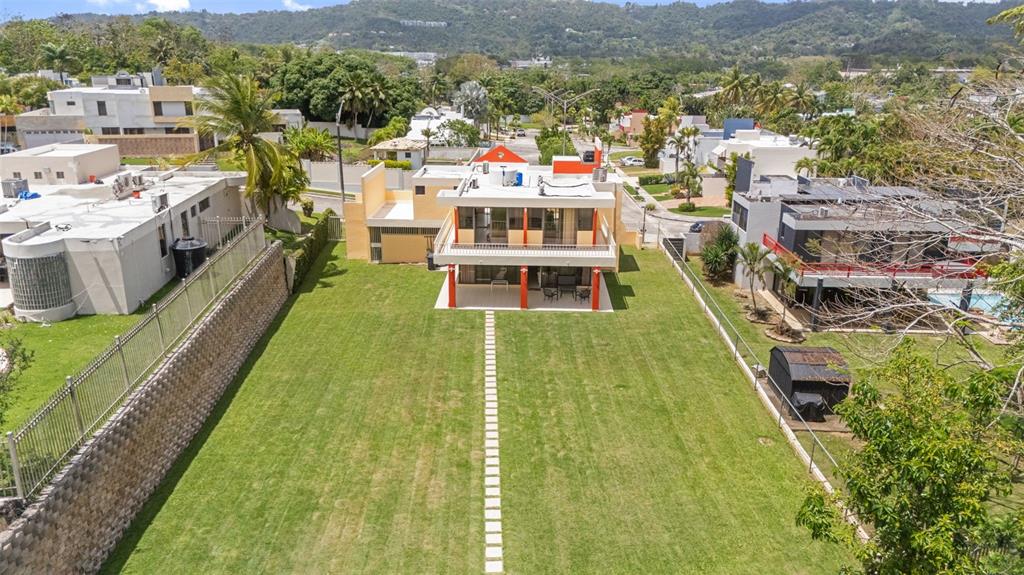 An aerial view shows a two-story house with a large backyard and stone wall — A16 SAN IGNACIO STREET, SAN PEDRO ESTATES, CAGUAS, PR