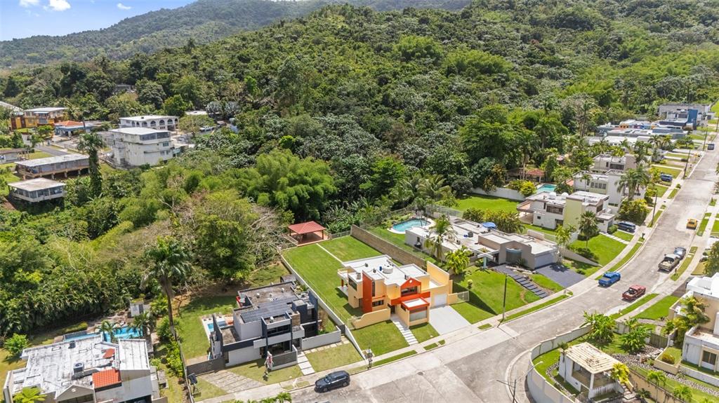 An aerial view shows several modern houses with swimming pools nestled near a forested hillside — A16 SAN IGNACIO STREET, SAN PEDRO ESTATES, CAGUAS, PR