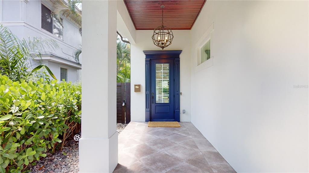 A covered front porch features a blue door, a globe pendant light, and tiled flooring — 1068 19TH AVENUE N, ST PETERSBURG, FL