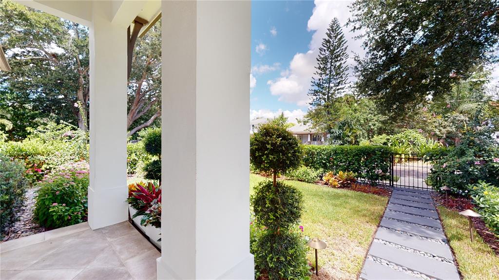 A view from a covered porch looking out toward a landscaped yard and stone walkway — 1068 19TH AVENUE N, ST PETERSBURG, FL