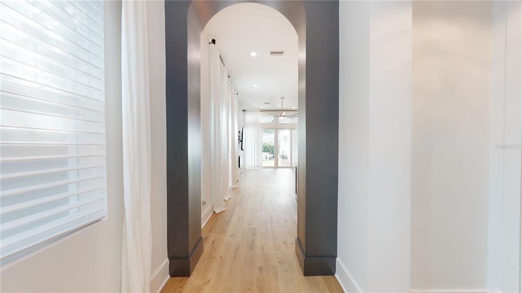 A hallway with light wood floors leads through a dark gray arched doorway — 1068 19TH AVENUE N, ST PETERSBURG, FL
