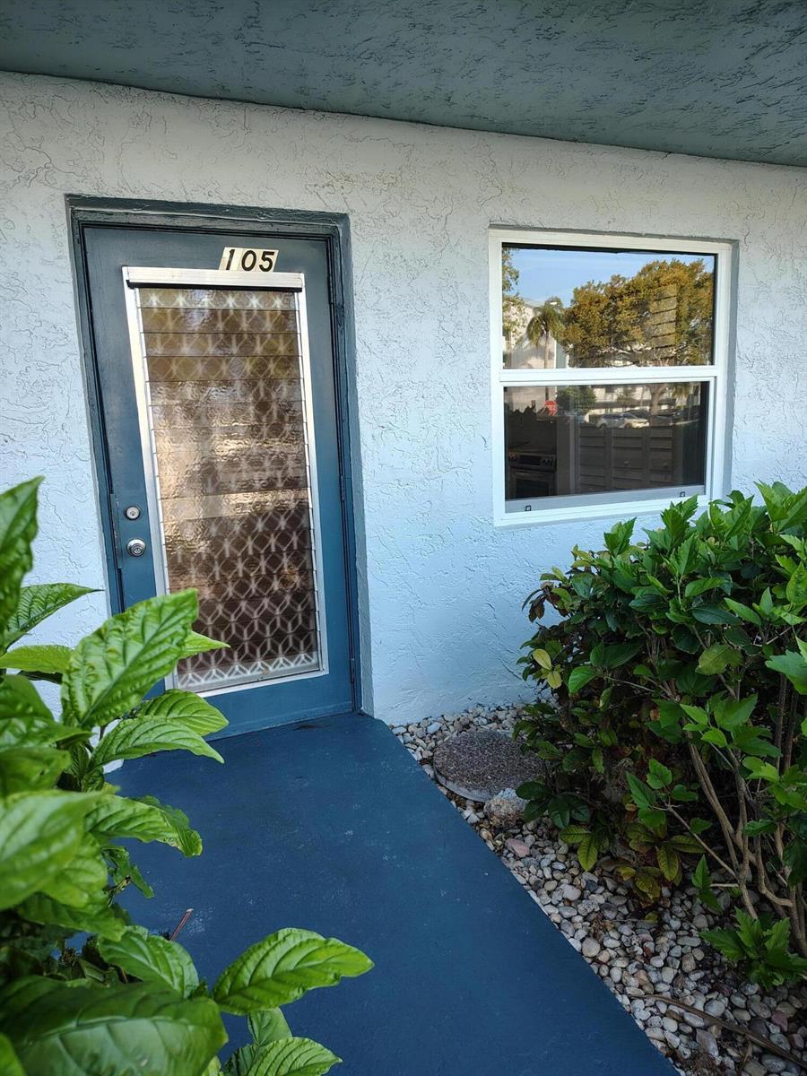 A blue front door labeled 105 sits next to a window on a stucco building exterior — 7680 NW 18th Street # 105, Margate FL 33063, MARGATE, FL