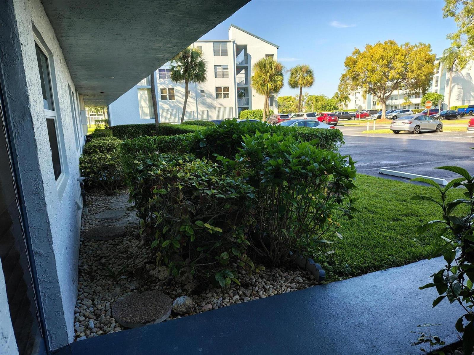 A view from a covered walkway looking out toward a parking lot and apartment buildings — 7680 NW 18th Street # 105, Margate FL 33063, MARGATE, FL