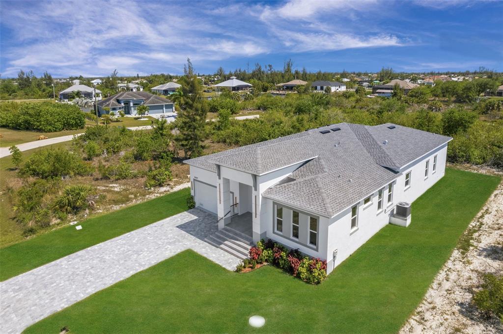 An aerial view shows a white single-story house with a gray roof and paved driveway — 15109 AQUARIUS CIRCLE, PORT CHARLOTTE, FL