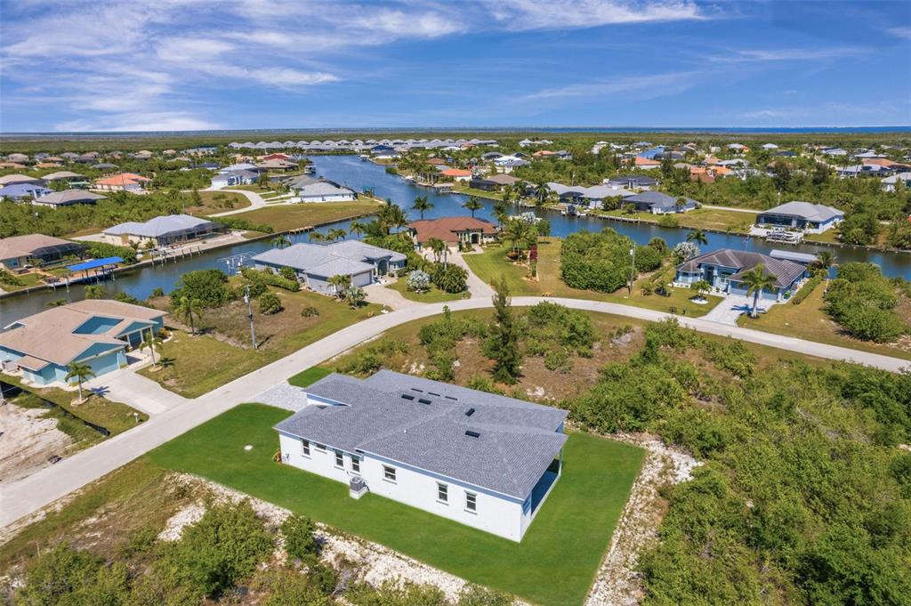 An aerial view shows a white house with a gray roof surrounded by lush vegetation — 15109 AQUARIUS CIRCLE, PORT CHARLOTTE, FL