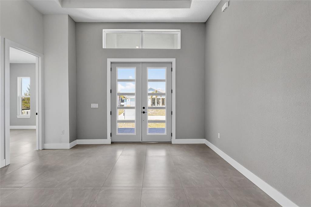 An entryway features gray walls, large floor tiles, double glass doors, and a transom window — 15109 AQUARIUS CIRCLE, PORT CHARLOTTE, FL