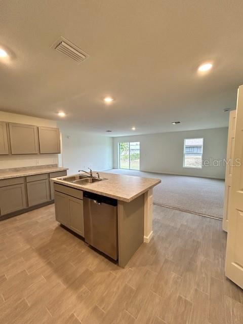 A kitchen with gray cabinets and a stainless steel dishwasher opens to a carpeted living area — 7354 ELLIS LANE, PORT CHARLOTTE, FL