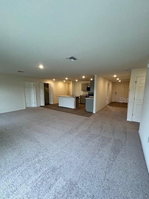 This open-concept living area features wall-to-wall carpeting and a kitchen with a central island — 7354 ELLIS LANE, PORT CHARLOTTE, FL