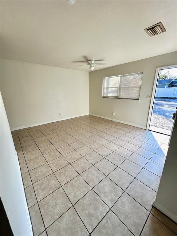An empty room with beige tile flooring, a ceiling fan, and a glass door — 9601 N 10TH STREET UNIT B, TAMPA, FL